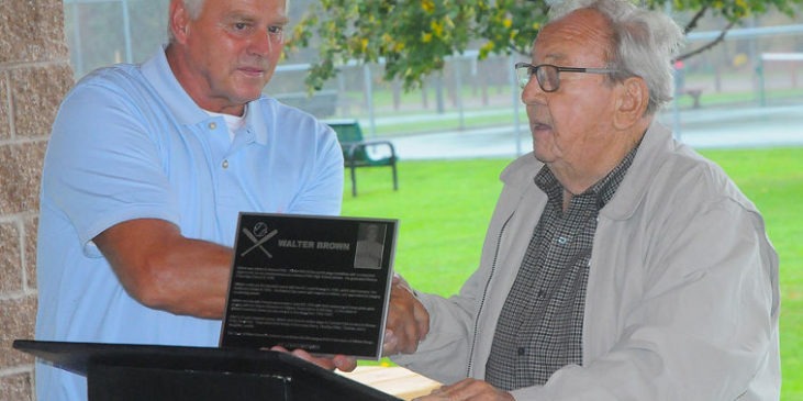 Town of Ellery supervisor Arden Johnson, right, presents a plaque to Tom Brown, son of the late Walt Brown, on Saturday. The town is dedicating a Little League field in the name of Walt, a Bemus Point native and former major league pitcher.